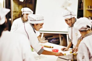 This picture shows several chefs preparing food together in a kitchen.