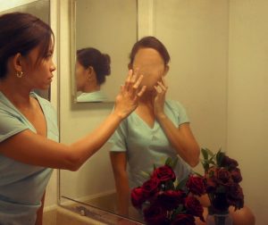 This picture shows a woman looking into the mirror and seeing a faceless reflection.