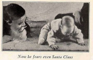 A photograph shows a man wearing a mask with a white beard; his face is close to a baby who is crawling away. A caption reads, “Now he fears even Santa Claus.”