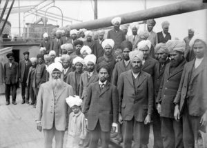 Immigrants from India on board the Komagata Maru. The group's leader, Gurdit Singh, wears a light-coloured suit. (Photo by Frank Leonard, Vancouver Public Library, Accession # 6231) https://commons.wikimedia.org/wiki/File:Sikhs_aboard_Komagata_Maru.jpg