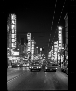 Even in the late 1960s, neon lights and rain-soaked streets in downtown Vancouver suggested film noir rather than suburban domesticity. Vancouver Public Library 43347.