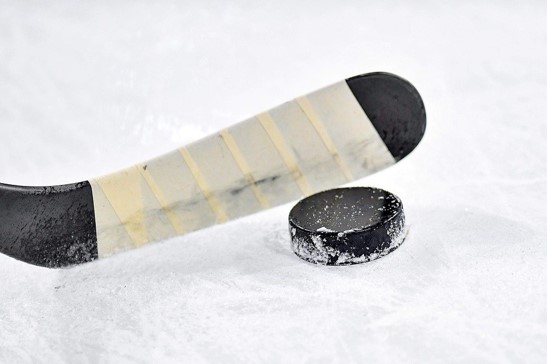 A hockey stick hitting a hockey puck