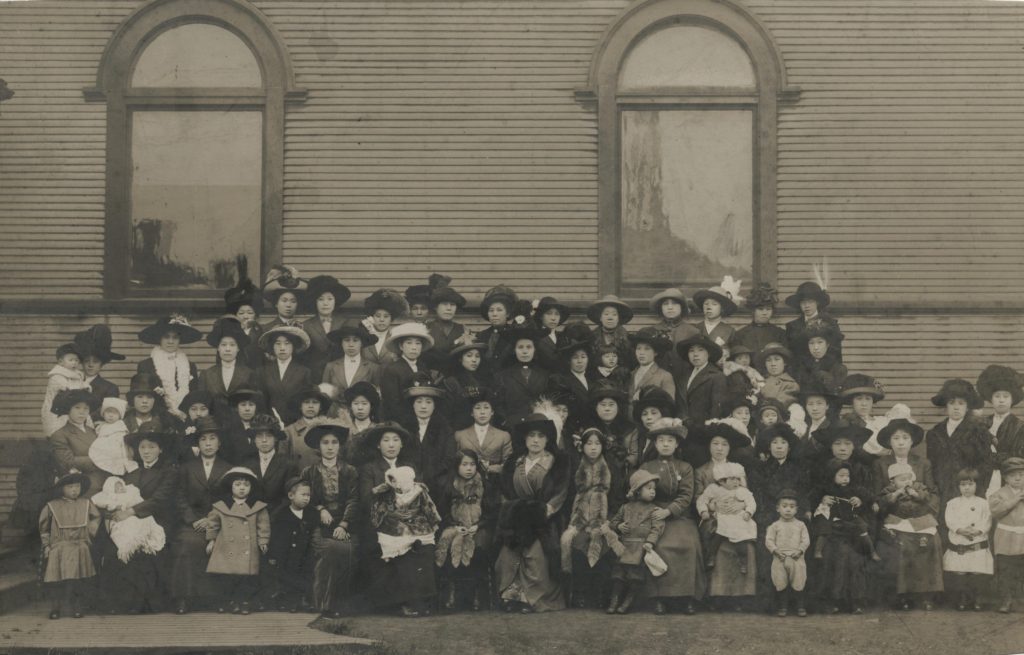 This photo depicts a sizable group of women and children posing in front of the Vancouver Japanese Buddhist Church building.