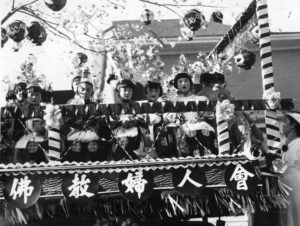 A photo of Buddhist Women’s Association-sponsored festival float. Children are sitting on the float, which is topped by a cherry blossom tree and paper lamps.