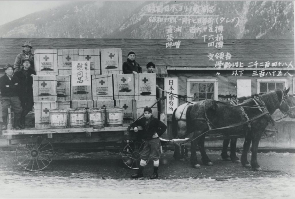 A photo of a group of six men posing next to a horse-drawn wagon carrying medical supplies.