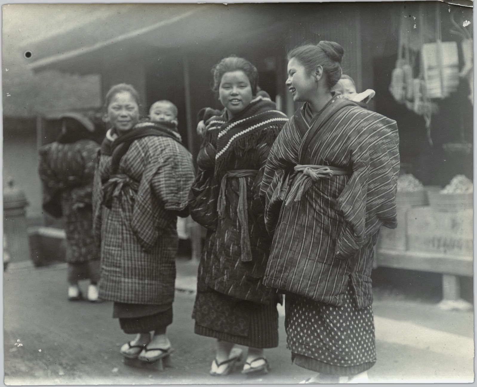 A photo of three smiling Japanese women, each carrying one infant on her back.