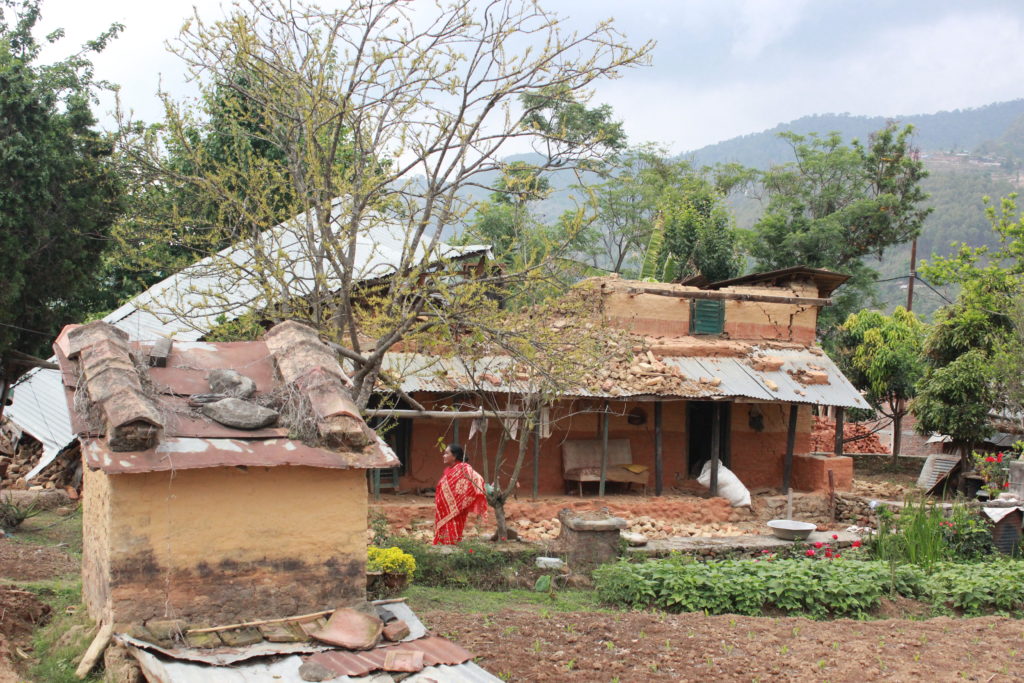 Woman in front of a house destroyed by an earthquake