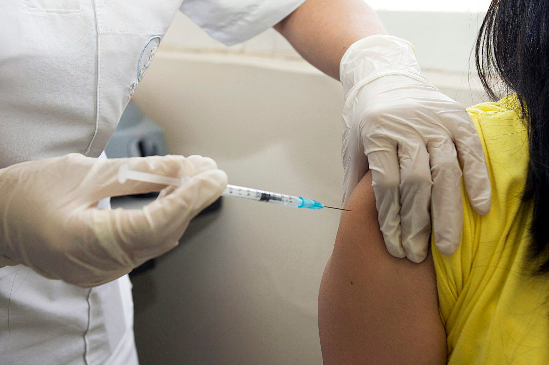 Close up of a woman recieving an injection in her arm.