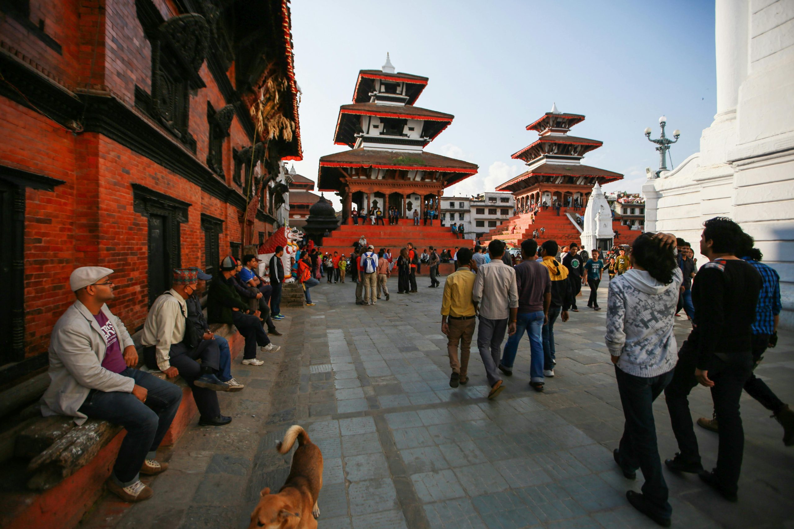 Historic street view of Durbar Square in Kathmandu, Nepal, with traditional temples and pedestrians in daylight.