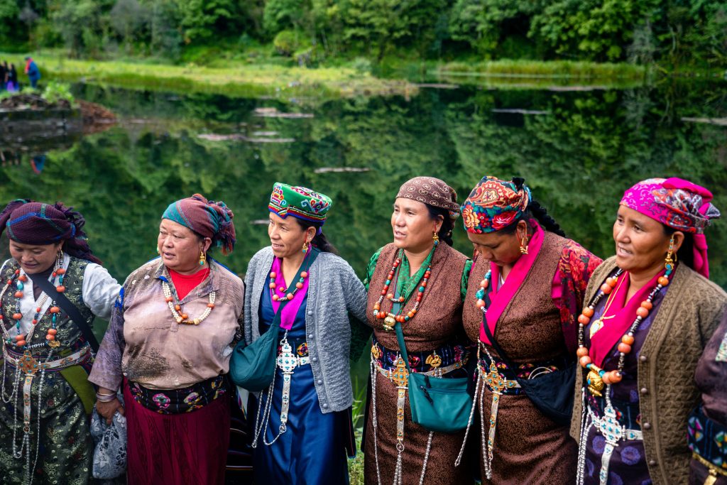 Tamang women in traditional dress smiling and standing together outdoors.