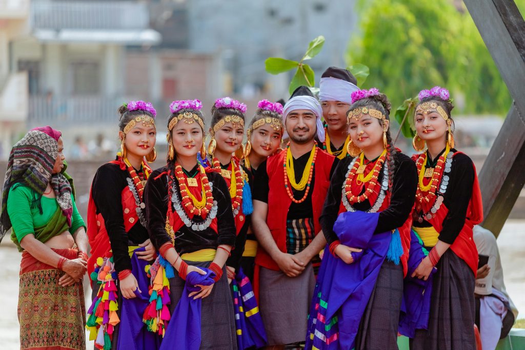 Group portrait of people in colorful traditional Nepali clothing and jewelry, posing outdoors in Butwal, Nepal.