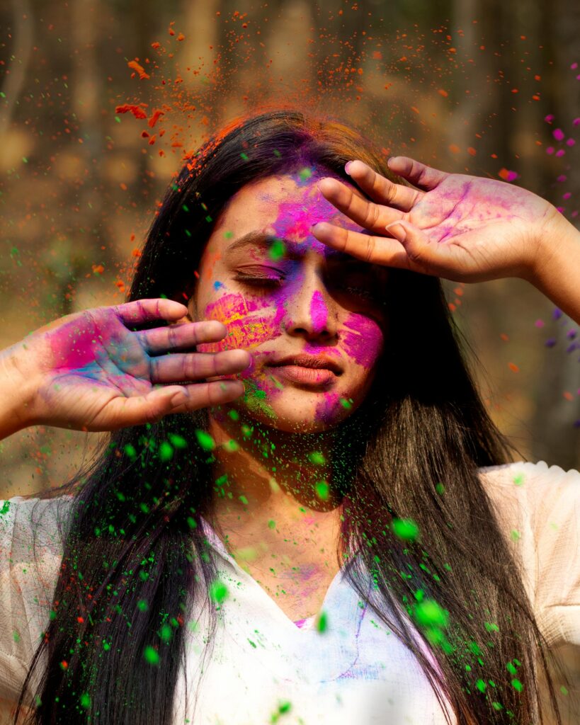Close-up portrait of a woman with colorful Holi powder on her face.