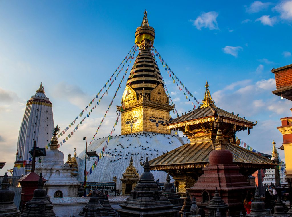 Swayambhunath Stupa with Buddha eyes and prayer flags under a clear blue sky, Kathmandu, Nepal.