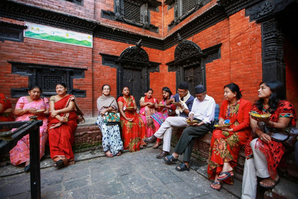 People sitting and eating beside a temple during a festival in Kathmandu, Nepal.