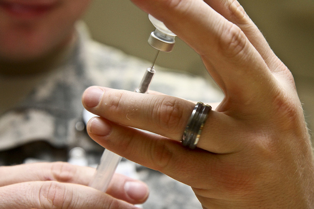 A doctor drawing a vaccine out of a vile