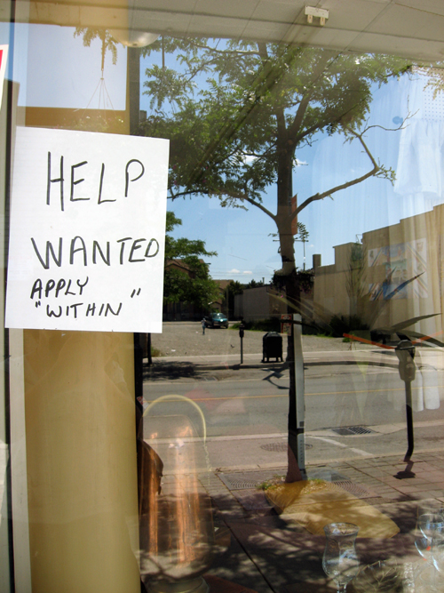 A help wanted sign on a restaurant window. It reads: