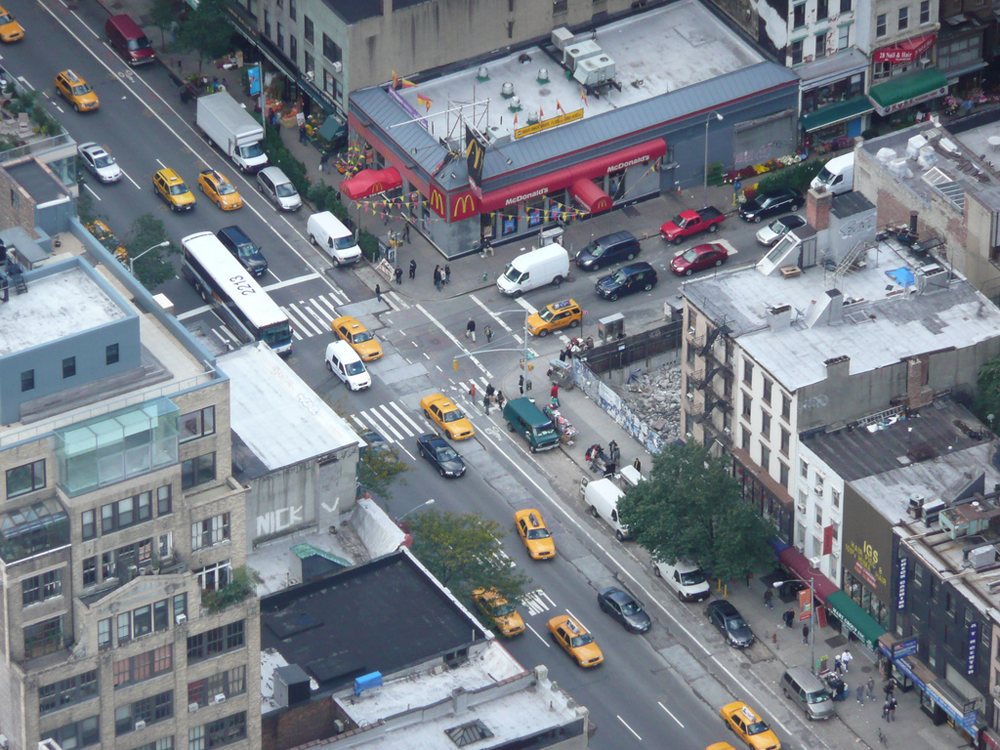 A busy traffic intersection in New York showing vehicles moving on the road.