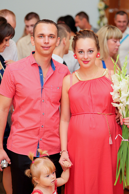 A couple smiling while holding hands with their young daughter