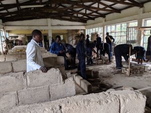 TVET instructor observing masonry students build a wall