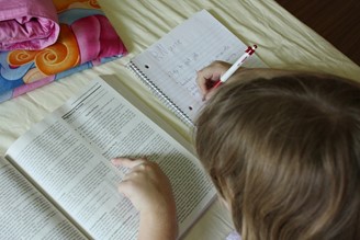 A child reading a textbook and taking notes.