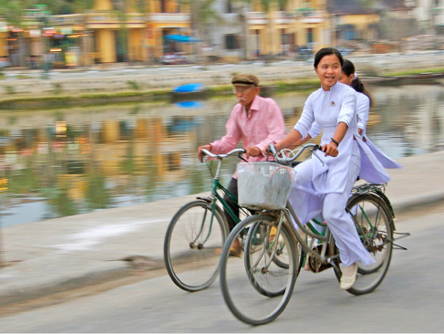 Picture shows three people riding bicycles next to a canal.