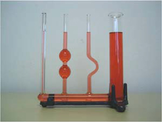 A photo of a few glass containers of different shape connected by a glass tube at the bottom and filled with red fluid. The fluid is at the same height at the different glass containers.