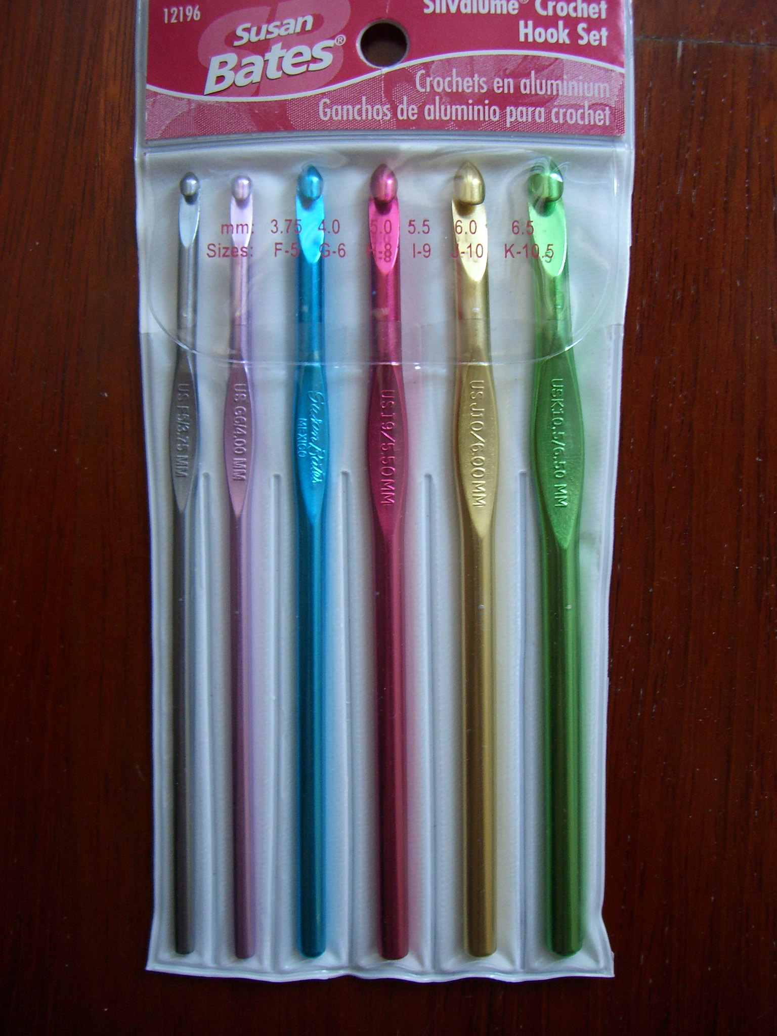 A plastic package holding several coloured pieces of flat metal that have hooks at the end.