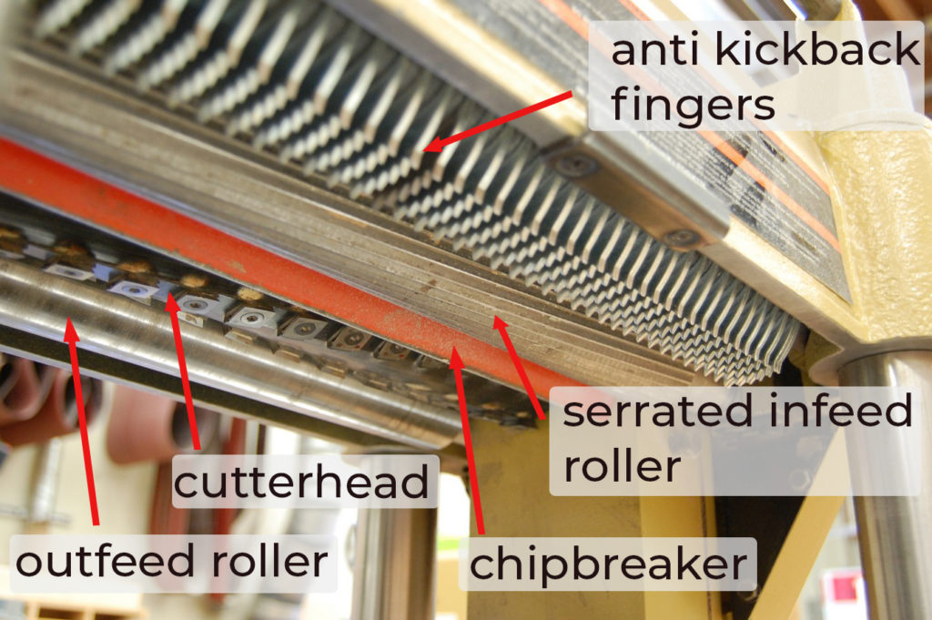Inside the planer head. Clockwise from top: anti-kickback fingers, serrated infeed roller. chipbreaker, cutterhead, outfeed roller