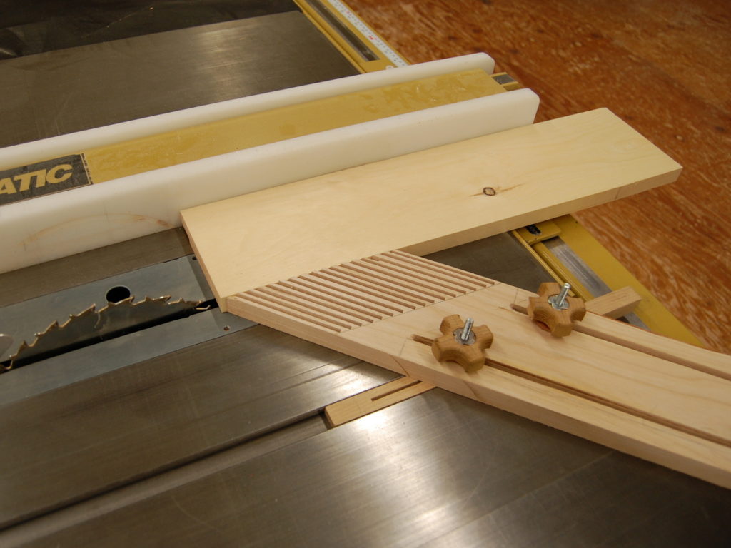 A featherboard being used to keep stock tight against the table saw rip fence.