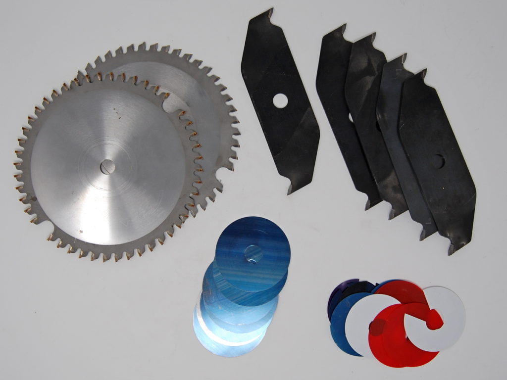 Dado blade set. Clockwise from top, chippers, plastic and metal dado shims, and the two outer saw blades